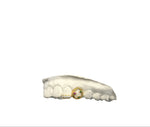 A set of gold-colored grillz with one tooth featuring three gemstones and the other with a diamond strip, on a white background.