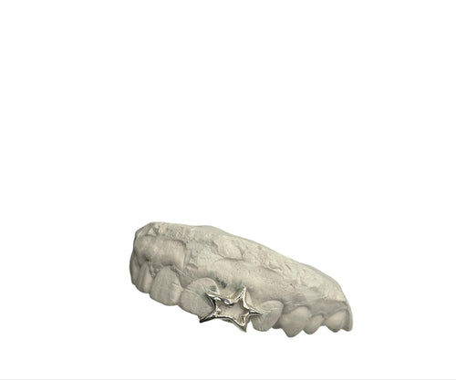 A silver tooth grillz with a liquid-style star design covering two teeth on a white background.